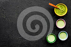 Brew matcha tea. Bowl with powder and cups with beverage on black background top view copy space