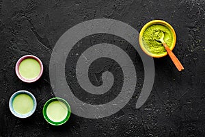 Brew matcha tea. Bowl with powder and cups with beverage on black background top view copy space