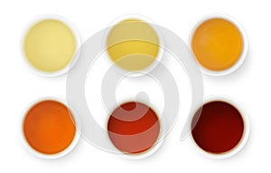 Brewed Chinese teas of different color in white bowls, top view isolated on white