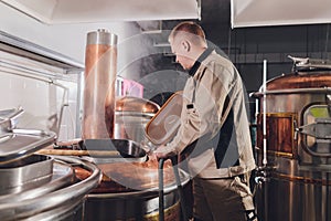 Brewer in brewhouse pouring out the malt to the tank.