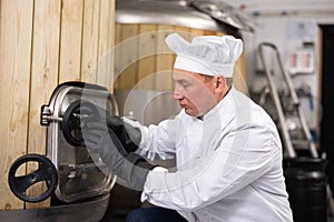 Brewer opens the hatch in the beer tank at brewery