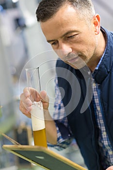 Brewer in uniform tasting beer at brewery