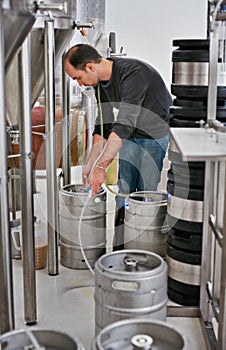 Brewery, man and pipe in tank with manufacturing for craft beer, alcohol and production process in factory. Industrial