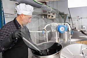 Brewery worker stirring raw materials in fermenter for beer production