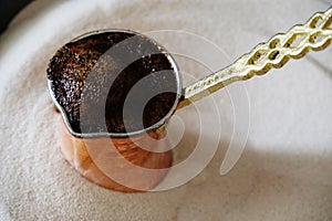 Brewing coffee in copper cezve on sand. Traditional turkish method