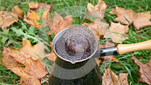 Brewing coffee in a turkish pot - outdoors over the autumn leaves photo