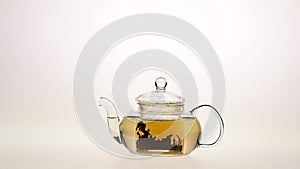 Brewing leaf tea in a transparent glass teapot. White background