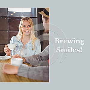 Brewing smiles text on grey with happy caucasain couple drinking coffees and talking in cafe