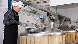 Brewmaster opening lid of fermenter while checking beer production process