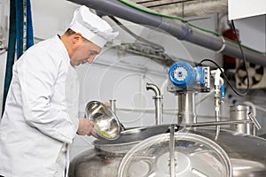 Brewmaster pouring hop pellets from bowl into beer production fermenter