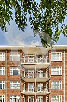 a brick apartment building with balconies and a tree