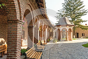 Brick arcades, wood benches in exterior court of Plumbuita Monastery, Bucharest, Romania