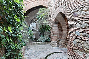 Brick arches and a fountain inside the Alcazaba of Malaga. Palatial fortification from the Islamic era built in the 11th century