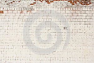 Brick background, the wall of an old brick building painted white with elements of destruction