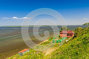 A brick building and green metal barrels with a combustible mixture on the shore of the lake.