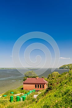 A brick building and green metal barrels with a combustible mixture on the shore of the lake.