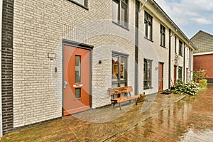 a brick building with an orange door and a bench