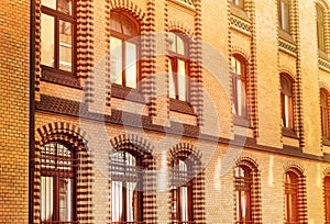 A brick building with shiny windows at sunset, beautiful sunlight reflected from the glass, the old architecture