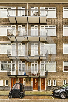 a brick building with three balconies and two cars
