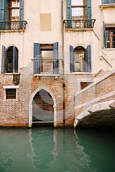 A brick building in the water in Italy, Venice. A brick bridge over a small narrow canal, classic Venetian windows in