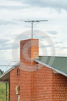 Brick building wild old fashion tv or radio antena with decorative facade and gray roof tiles with white trim