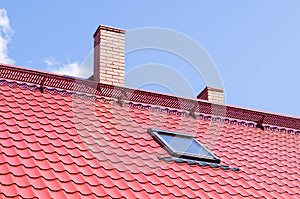 Brick chimney on red roof with mansard window