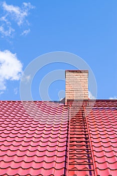 Brick chimney on red roof with metal ladder