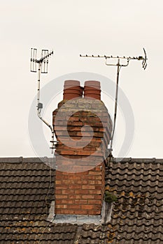 Brick chimney stack and TV aerials on English rooftop photo