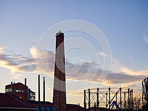 A brick chimney stands tall against the cloudy dusk sky in the city afterglow photo