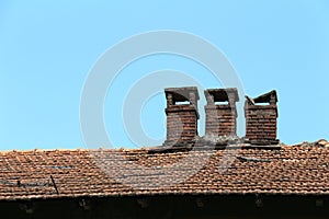 Brick chimney on tile roof of an old wooden house