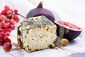 Brick of cow milk cheese with herbs and spices