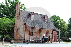 A brick farmhouse with an open storage shed and farming tools