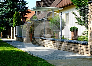 Brick fence piers with metal mesh panels. formal gareen garden and house in the background