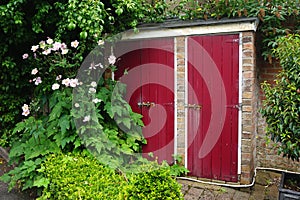 Brick garden shed with bright red doors