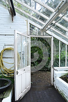 Brick and glass old vintage greenhouse with open to the garden door