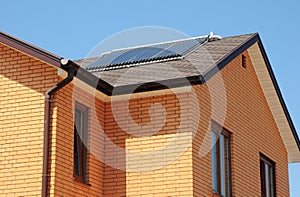 Brick house asphalt shingles roof top with solar water heater, solar water heating panels