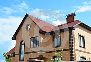 Brick house with attic window rain gutter system and red asphalt