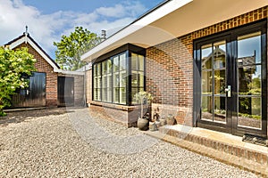 a brick house with black doors and a gravel driveway