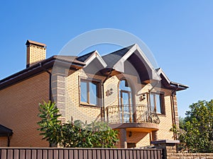 Brick house exterior with forgery balcony, rain gutters and brick chimney with beautiful forging