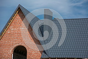 Brick house with grey metal tile roof, hole for window