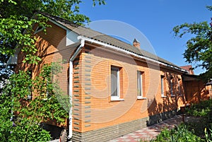 Cozy brick house with old asbestos roof. Rain gutter and brick wall.