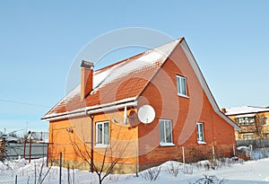 Brick House with red metal roof tile and chimney covered snow in winter