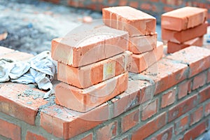 Brick house wall constuction with stack of red bricks. Building house brick wall concept photo