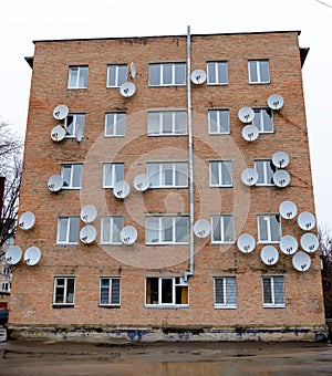 Brick house on the wall of which is attached a lot of satellite dishes