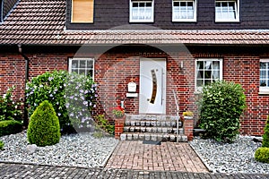 Brick house with white door and steps leading to the front door in Germany