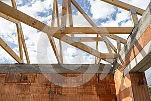 Brick house with wooden roof truss, support beams and ceilings under blue sky