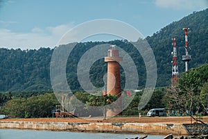 Brick lightho use on the shore, against the background of the jungle. Asia