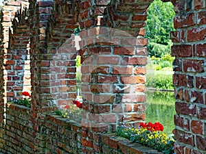 Brick masonry arches with flowers on window sills and view to pond and park