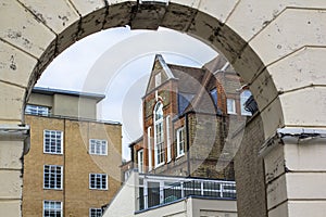 Brick multi-level house with large beautiful windows. Picture taken through the old arch. Central London.