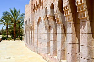 Brick old ancient carved Arab Islamic Islamic wall with ornaments and patterns against the background of green tropical palm